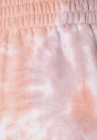 Tissu tie-dye rose avec une texture douce et une taille élastique. Le dégradé de couleurs comprend des nuances de rose claires et foncées.