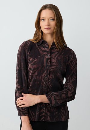 Zwarte en bordeauxblauwe blouse met verticale streepjes en abstract patroon, met een knoopsluiting aan de voorkant en lange mouwen.