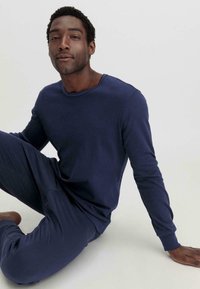 Set aus einem navyblauen Langarmhemd und einer Hose aus weichem Stoff, mit Rundhalsausschnitt und eng anliegenden Bündchen, in glatter Textur.