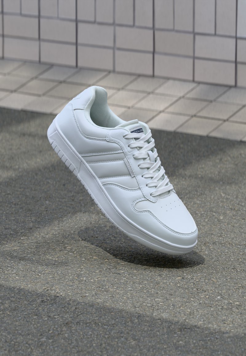 Λευκό αθλητικό sneaker με λείο δερμάτινο άνω μέρος, κορδόνια μπροστά, τρυπητή μύτη και σχεδιασμένη σόλα. Μινιμαλιστικός σχεδιασμός με τρεις πλευρικές ρίγες.