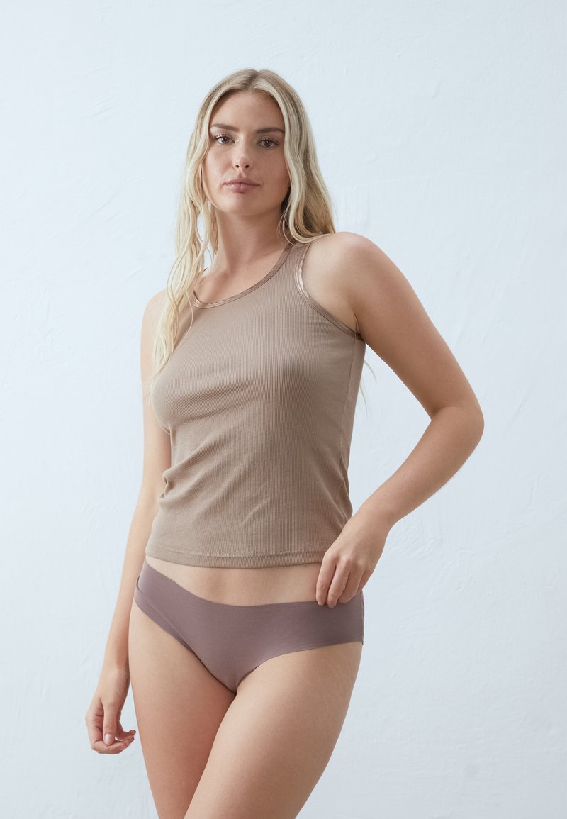 Bruine geribbelde tanktop met een ronde halslijn, gecombineerd met mauve naadloze ondergoed. Zachte textuur en aansluitend ontwerp. Minimalistische stijl.