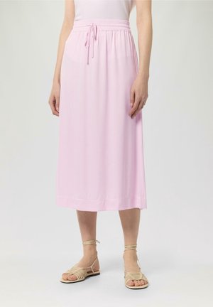 Jupe midi rose clair avec une taille élastique et un cordon de serrage. Tissu lisse drapé doucement. Associée à des sandales à talons beiges.