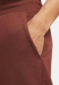Brown jersey pants featuring a side pocket with a textured finish. The fabric appears soft and slightly stretchy.