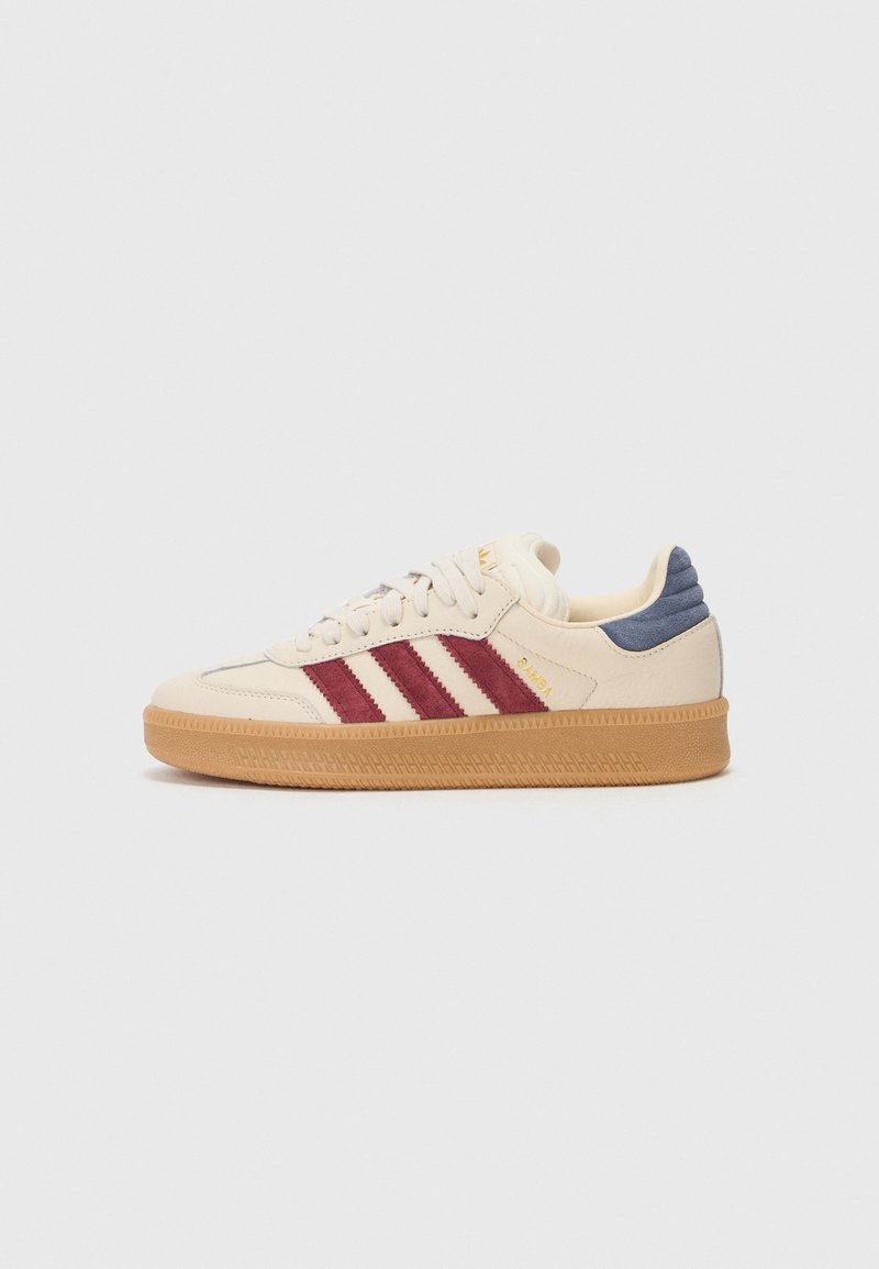Cream leather sneakers feature maroon stripes, a light blue back tab, and a gum rubber sole with textured tread patterns.