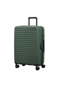 Valise rigide verte avec un design à stries texturées, poignée rétractable noire et quatre roues pivotantes pour une facilité de déplacement.