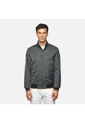 Chaqueta bomber gris con delantero de cremallera, dos bolsillos frontales y puños acanalados con acentos naranjas. Fabricada en un tejido ligero y suave.