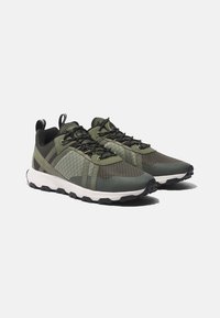 Grüne Sportschuhe mit einem Mesh-Obermaterial, strukturierten Akzenten, schwarzen Schnürsenkeln und einer weißen Zwischensohle sowie einer Gummisohle für gute Haftung.