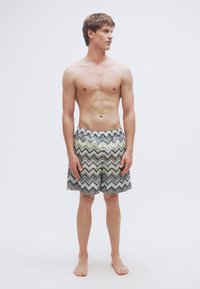 Ανδρικά μαγιό τύπου σορτς με σχέδιο ζιγκ ζαγκ σε αποχρώσεις του γκρι και του κρεμ, με ελαστική μέση και άνετη εφαρμογή.