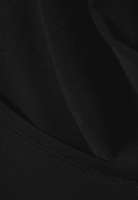 Schwarzer Stoff mit einer glatten, dehnbaren Textur und einem leicht glänzenden Finish. Enthält eine Naht entlang der unteren Kante.