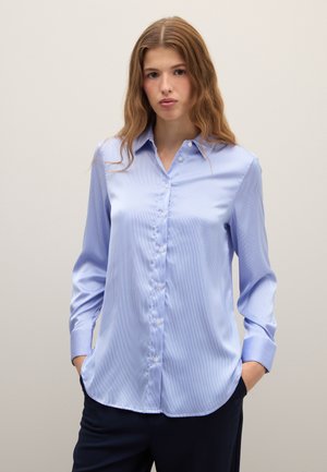 Lichtblauw overhemd met verticale strepen, zacht materiaal, puntige kraag en lange mouwen. Gebogen zoom en knoopdetails zichtbaar.