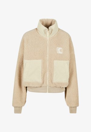 Giacca in fleece beige con colletto alto, chiusura con zip, due tasche frontali e polsini a costine. Presenta un logo sul lato sinistro del petto.