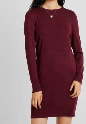 Vinrød strikkjole med lange ærmer, rund hals, ribbede manchetter og kant. Blød tekstur, tætsiddende silhuet og minimalistisk design.