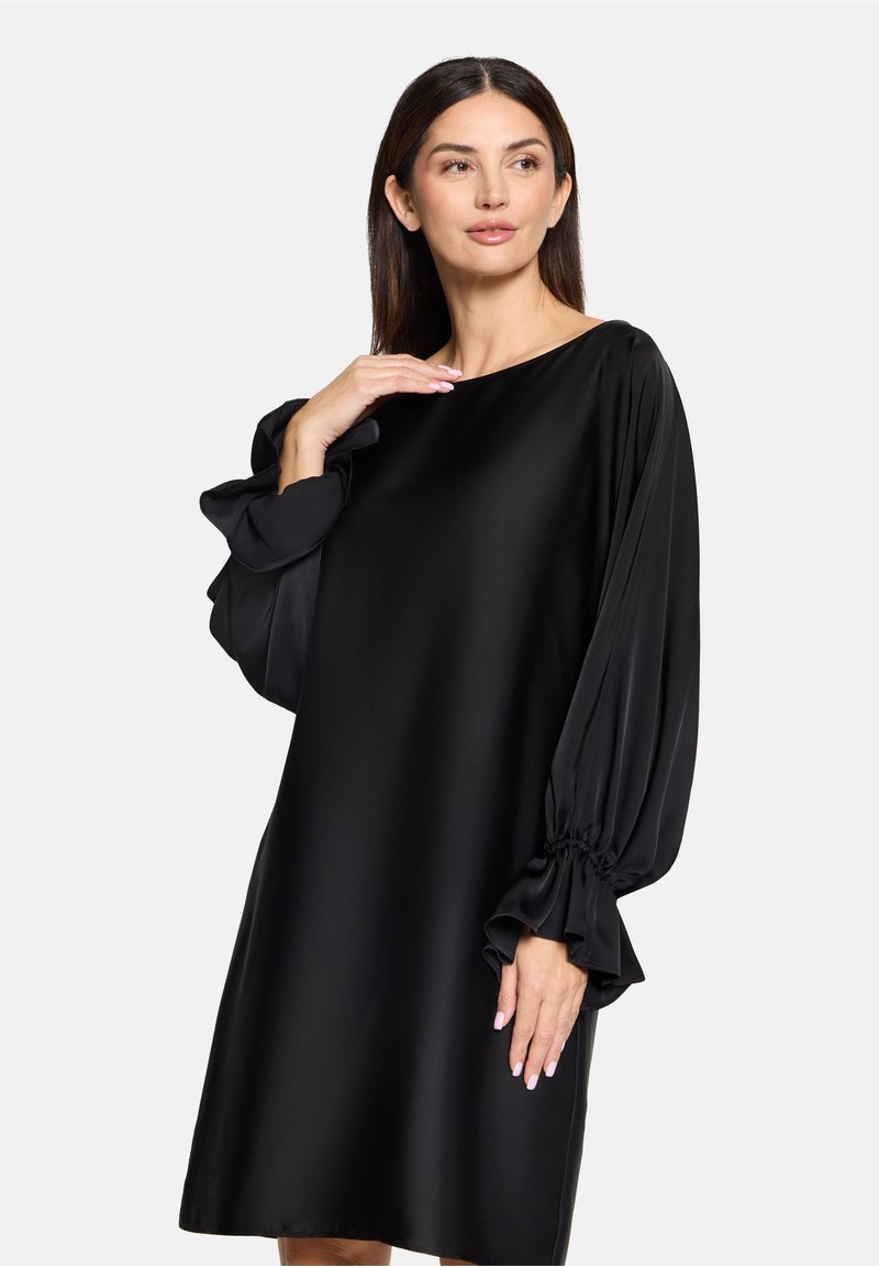 Czarna sukienka o luźnym kroju, z długimi, bufiastymi rękawami i marszczonymi mankietami. Wykonana z gładkiego materiału z okrągłym dekoltem.