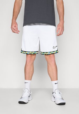 Pantaloni sportivi bianchi con un bordo colorato e fantasioso all'orlo, caratterizzati da un logo Nike nero, abbinati a scarpe atletiche bianche e calze.