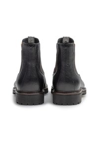 Botas de tobillo de cuero negro con un acabado texturizado, paneles laterales elásticos y pequeñas lengüetas en la parte trasera. Suelas de goma sólida con dibujos.