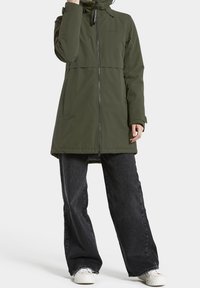 Parka impermeable verde oliva con cierre de cremallera, cuello alto y un corte relajado. Presenta mangas largas y llega a la mitad del muslo.