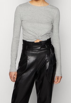 Šedý dlouhý rukáv crop top s předním uzlem, kombinovaný s černými vysokým pasem z umělé kůže, který má široký pásek a boční zavazování.