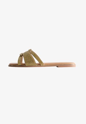 Sandalias planas con una correa adornada con Strass dorados, diseño de punta abierta y suela sintética en tono bronceado. Textura suave y forma minimalista.