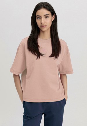 Hellrosa oversized T-Shirt aus weichem Stoff mit kurzen Ärmeln und rundem Halsausschnitt. Besticktes Logodetail auf der Brust.