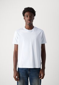 Světle modré bavlněné tričko s krátkými rukávy, kulatým výstřihem a decentním potiskem loga "MARC O'POLO DENIM" na hrudi. V kombinaci s džíny.