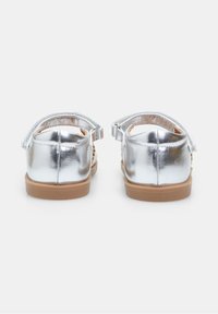 Srebrne metaliczne sandały z odkrytym tyłem, regulowanym paskiem i gumową podeszwą; z plecionym zdobieniem po bokach.