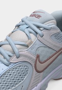 Hellblauer und weißer Nike-Sneaker mit Mesh-Gewebe, hellblauen Schnürsenkeln und einem pinkfarbenen Nike-Swoosh an der Seite.
