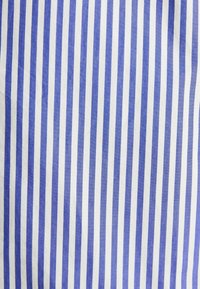 Bavlnená tkanina s vertikálnymi pruhmi v modrej a bielej farbe, s rovnomernými, stredne širokými líniami a hladkou textúrou. Ideálna pre rôzne textilné aplikácie.