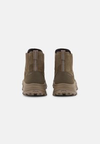 Botas de tobillo impermeables marrones con un acabado de ante texturizado, una lengüeta y rayas verticales en contraste. Presenta una suela de goma resistente.