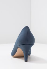 Chaussure à talons hauts en satin bleu avec un bout pointu, un talon aigu slender et une texture lisse. Vue arrière montrant un design sans coutures.