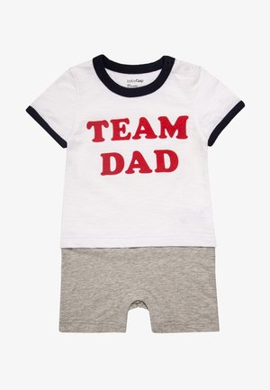 Weißer Baby-Strampler mit marineblauem Besatz und rotem "TEAM DAD"-Schriftzug auf der Vorderseite, kombiniert mit angenähten grauen Shorts.