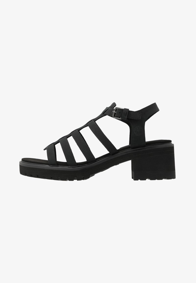 Sandale en cuir noir avec plusieurs brides, fermeture à boucle et talon bas épais, conçue pour un usage décontracté.