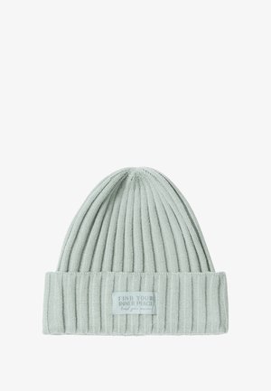 Gorro de punto acanalado verde claro con una vuelta doblada. Presenta una etiqueta con el texto "ENCUENTRA TU PAZ INTERIOR". Textura suave y ajuste ceñido.