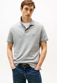 Grijze polo met korte mouwen, een kraag en een klein logo. Gecombineerd met donkerblauwe denim jeans en een geweven zwarte riem. Eenvoudig en casual ontwerp.