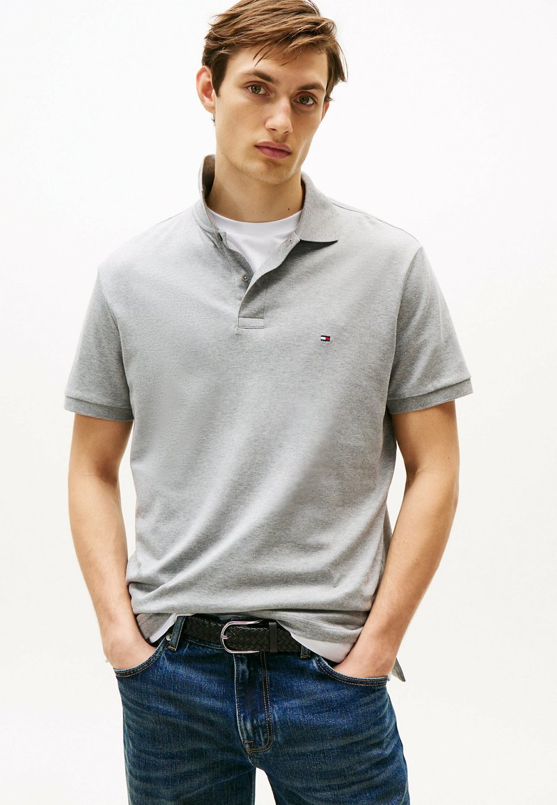 Grijze polo met korte mouwen, een kraag en een klein logo. Gecombineerd met donkerblauwe denim jeans en een geweven zwarte riem. Eenvoudig en casual ontwerp.
