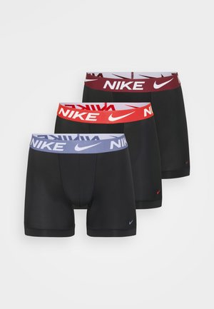 Tri pary črnih raztegljivih bokseric s kontrastnimi blagovnimi pasovi v rdeči, vijolični in maroon barvi, na katerih je vidno prikazana Nike logotip.