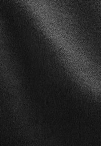 Matière en feutre noir doux avec une texture subtile, présentant une surface lisse et de légères variations d'ombrage ainsi que des reflets de lumière.