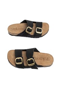 Sandali con fascia in suede nero, dotati di due fibbie regolabili in oro, con soletta in sughero e suola in gomma testurizzata. Made in Spain da Yokono.