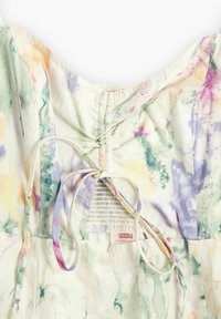 Robe en coton avec un imprimé aquarelle pastel comprenant du vert clair, du violet et de l'orange. Comprend des fronces à l'arrière et une fermeture à nouer.