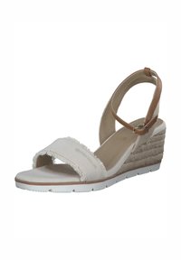 Sandale compensée en toile blanche avec détails de lanière effilochée, lanière de cheville beige, talon compensé texturé et semelle en caoutchouc blanche.