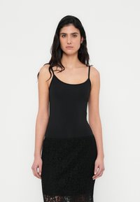 Top nero a spalline sottili in tessuto liscio, design aderente, abbinato a una gonna nera in pizzo con intricati motivi floreali.