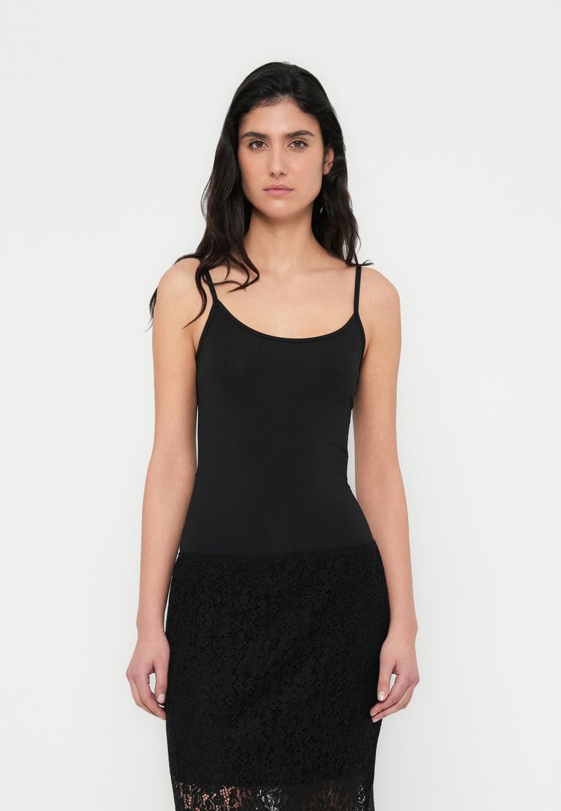 Top nero a spalline sottili in tessuto liscio, design aderente, abbinato a una gonna nera in pizzo con intricati motivi floreali.