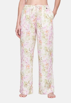 Lockere Loungehose mit Blumenmuster, Kordelzug in der Taille und seitlichen Taschen, getragen von einer stehenden Person, barfuß vor weißem Hintergrund.