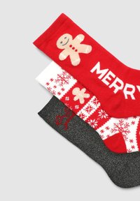 Tre paia di calzini festivi: rossi con un omino di pan di zenzero, bianchi con fiocchi di neve e neri glitter con testo rosso. Materiale in misto cotone.
