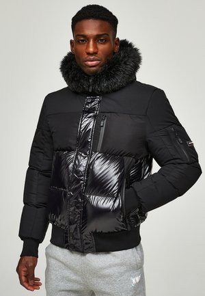 Black puffer jacket with a glossy midsection and matte sleeves, featuring a faux fur collar and multiple zippered pockets.