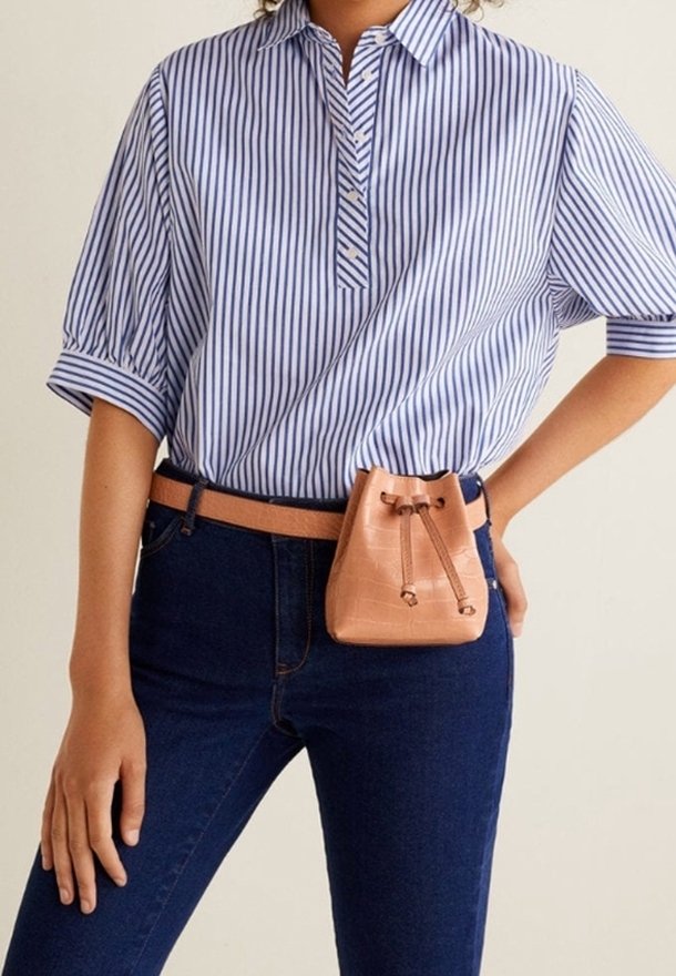 Chemise à manches courtes rayée bleu et blanc, associée à un jean foncé et un petit sac à cordon en cuir de couleur pêche.