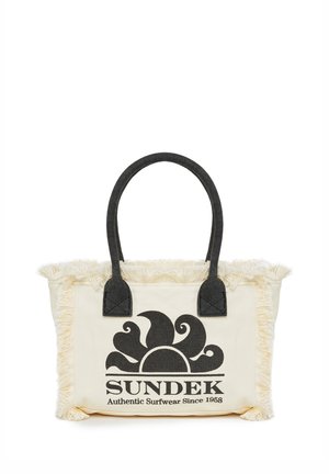 Crème canvas tas met zwarte handvatten, franjes aan de randen en een zwart zon-logo met de tekst "SUNDEK Authentic Surfwear Since 1958" aan de voorkant.