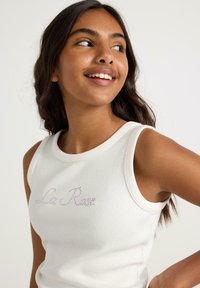 Hvid ribbet tanktop med et pink broderet "La Rive" design foran. Glat tekstur og ærmeløst design med rund halsudskæring.