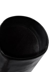 Zwarte leren laars, met een gladde buitenkant en een zachte suède binnenkant. Ronde opening met omgeslagen rand, minimale stikseldetails.
