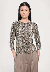 Long-sleeve top with a snake print pattern in tan and black. Features a round neckline and slim fit, paired with beige wide-legged trousers.