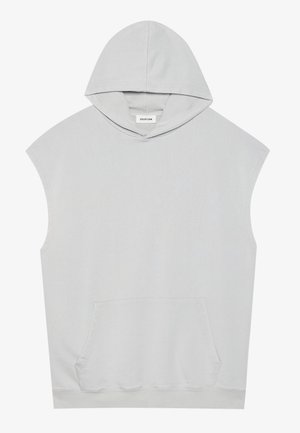 Bezrękawnik w jasnoszarym kolorze z kapturem, przednią kieszenią kangurką, luźnym krojem i małą metką marki wewnątrz przy szyi.